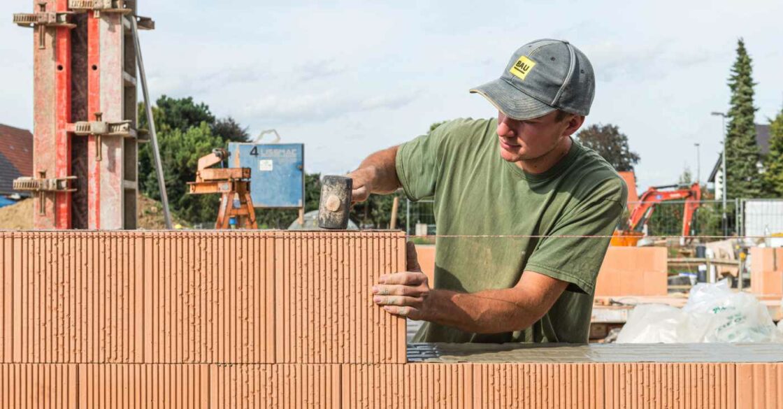 Handwerker auf der Baustelle beim Erstellen eines Ziegelmauerwerks.