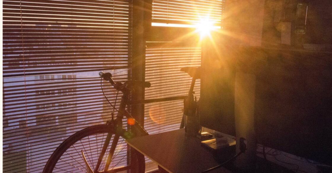Fahrrad abgestellt in der eigenen Wohnung. Die Sonne scheint durch die Jalousie.